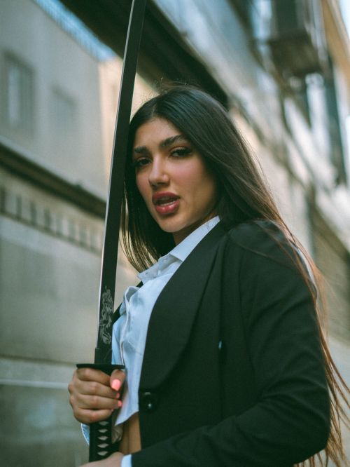 Free A young woman confidently holding a sword in an outdoor urban setting. Stock Photo
