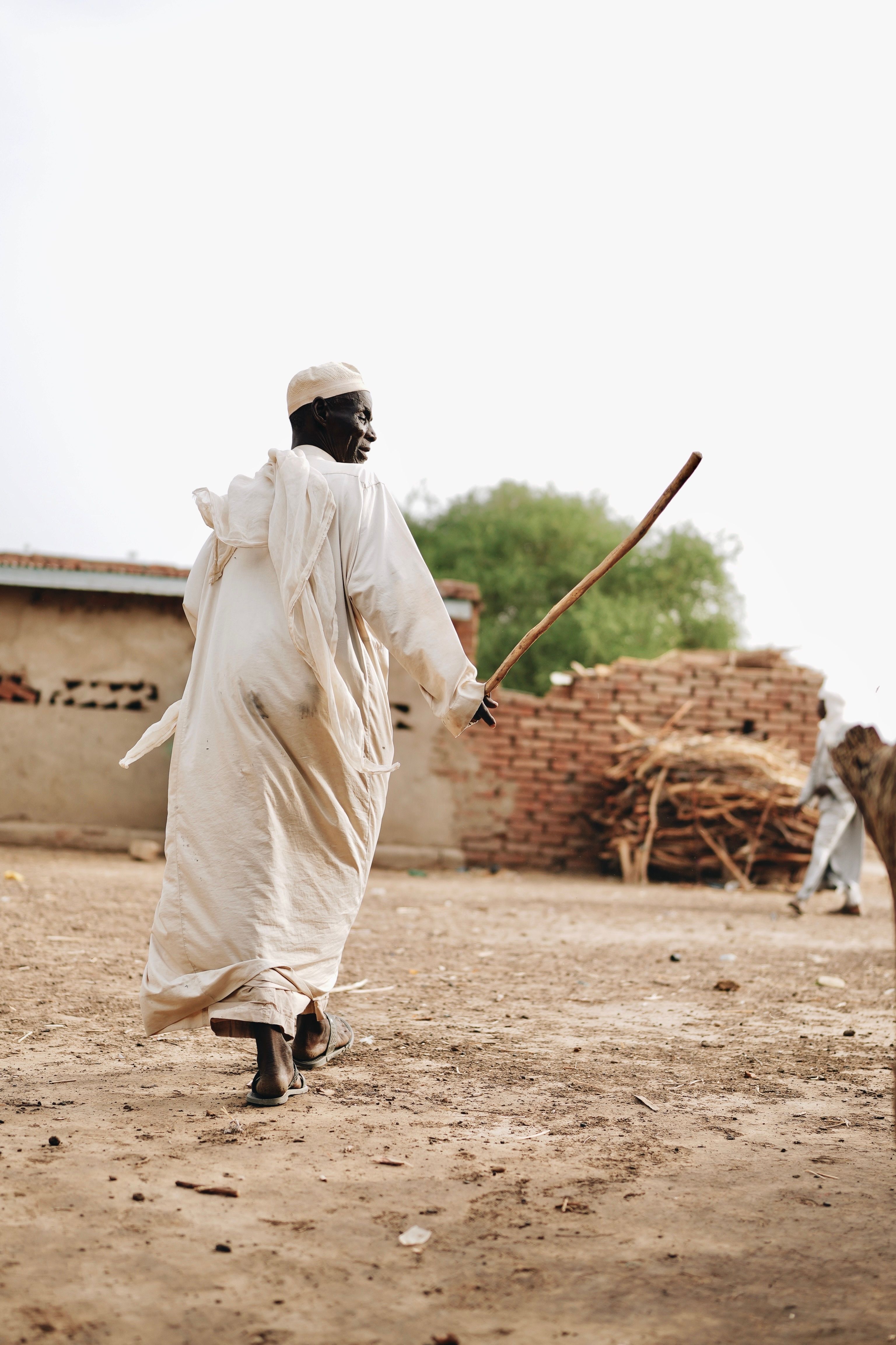 African Man Standing by Straw Structure in Desert · Free Stock Photo