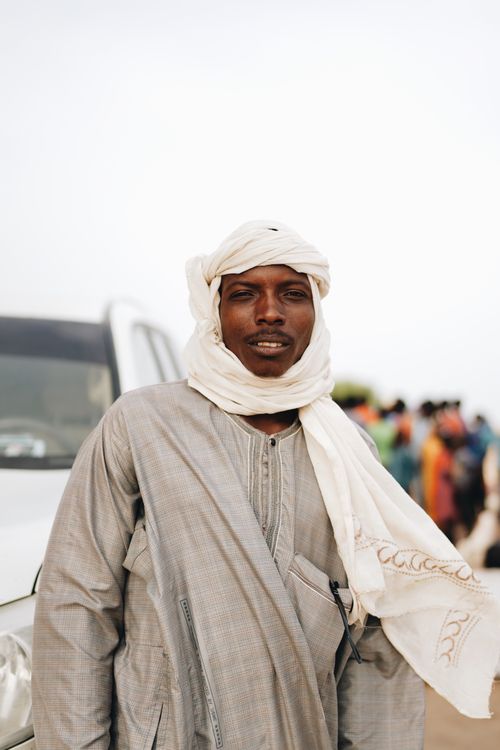 Free Man in traditional attire with a vehicle in the background, outdoors. Stock Photo