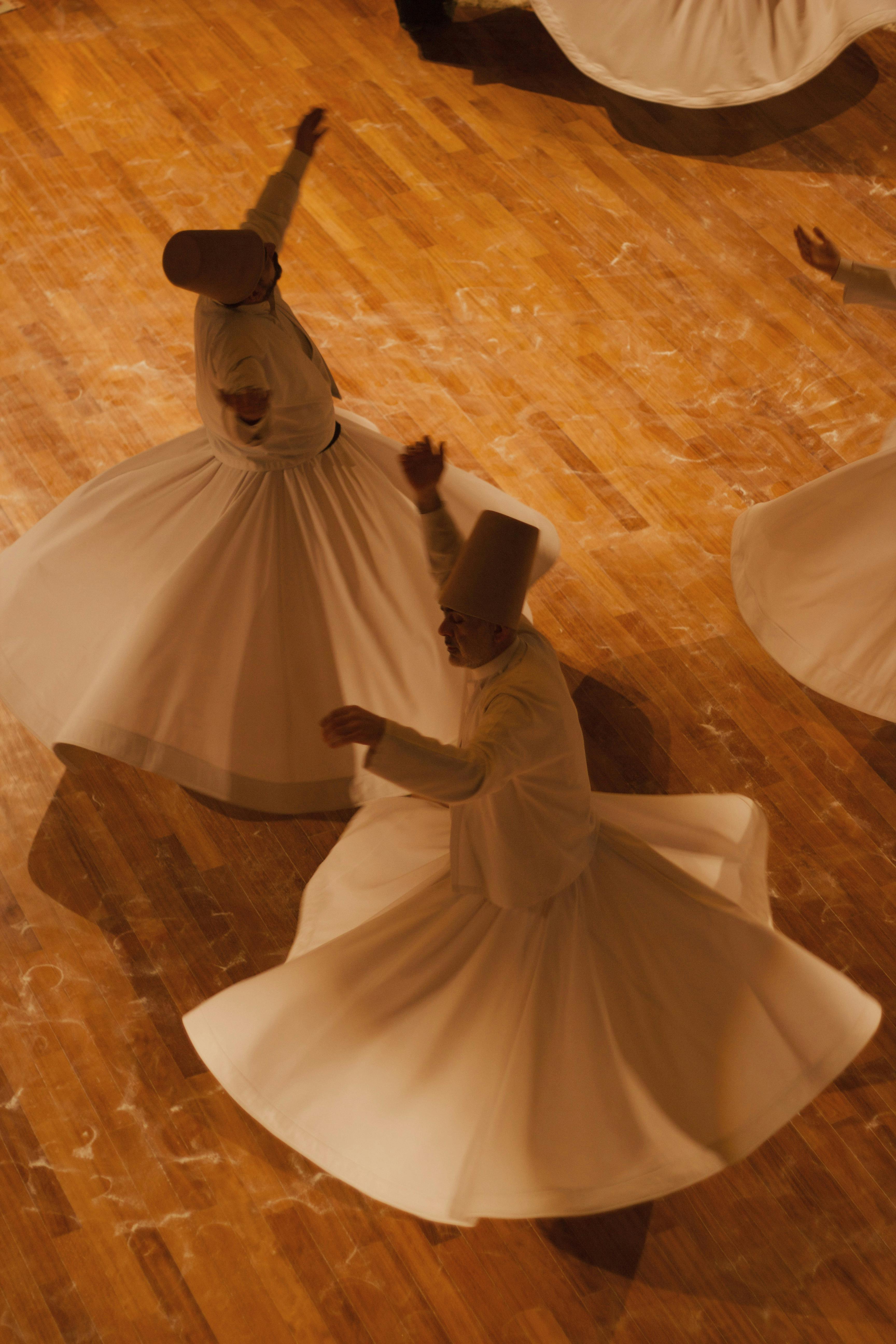Authentic Sufi whirling dervishes spinning gracefully on wooden floor.
