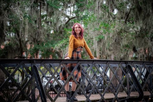 A woman stands confidently on a bridge surrounded by lush greenery in Savannah, Georgia.