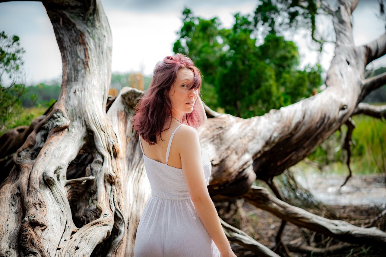 woman standing by a gnarled tree in savannah georgia exuding a serene