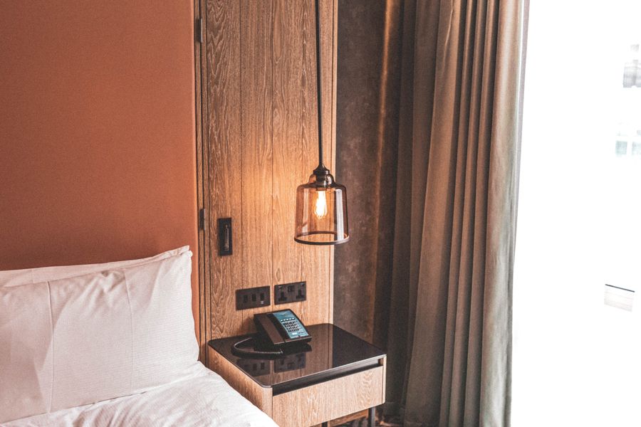 A bedroom corner with a warm pendant lamp