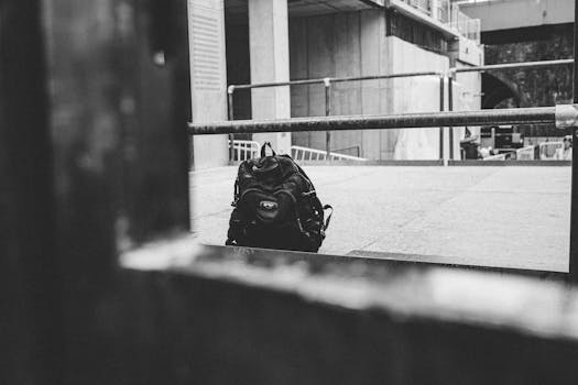 Black-and-white photo of an abandoned backpack in a minimalist urban environment.
