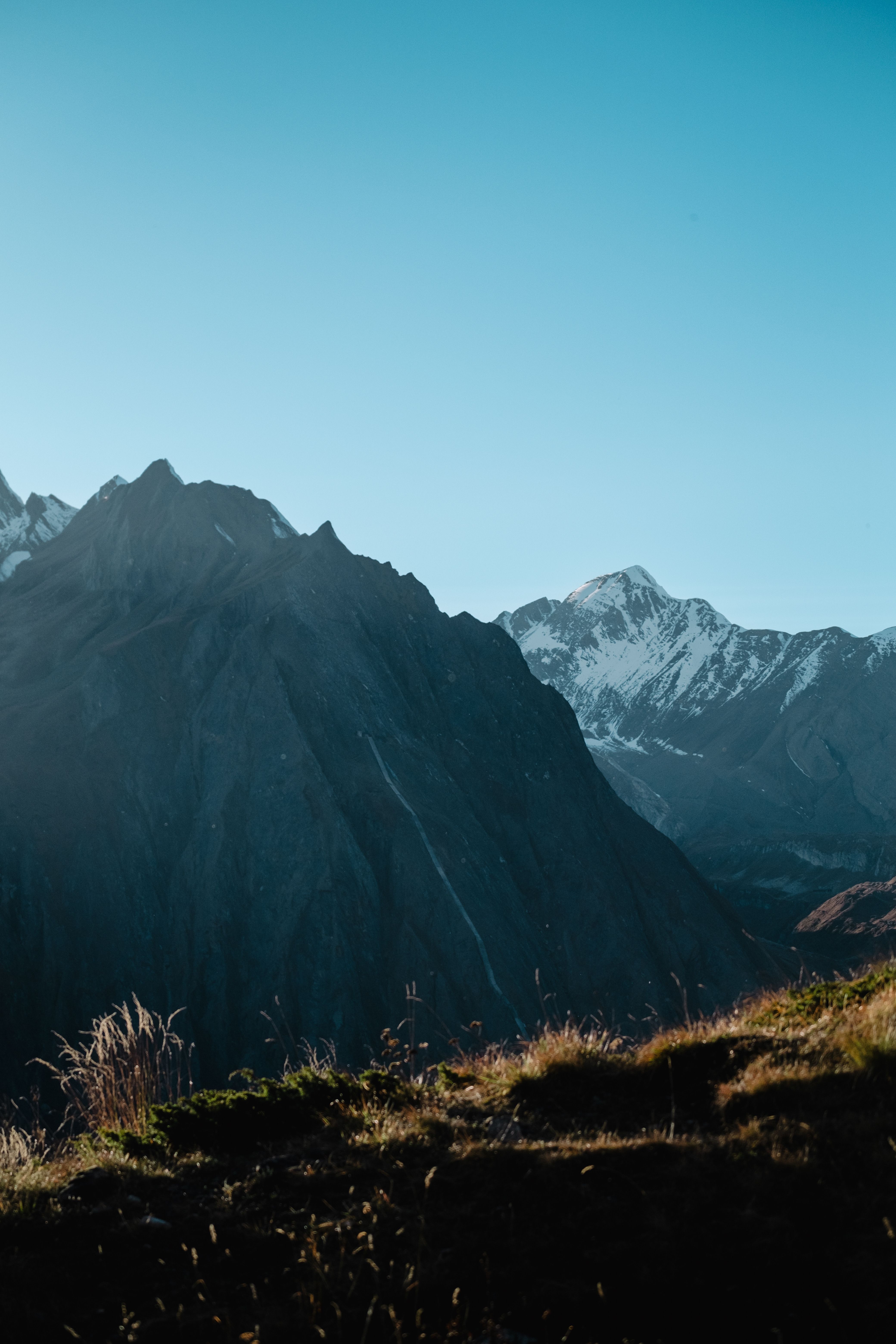 Stunning view of a snow-capped mountain range under a clear blue sky at sunrise.