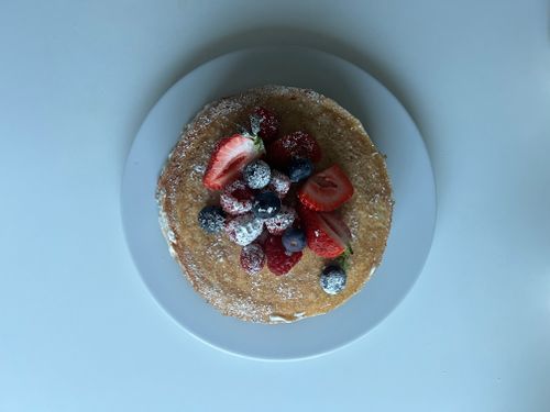 Free Stack of pancakes topped with fresh strawberries, blueberries, raspberries, and powdered sugar. Stock Photo