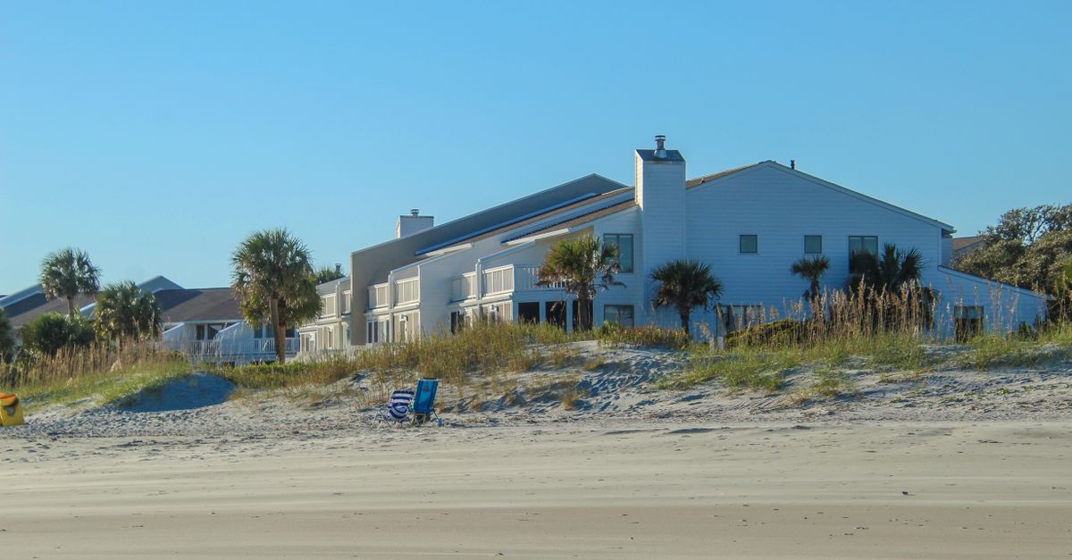 Beachfront houses with palm trees under a clear blue sky, showcasing a serene coastal setting.