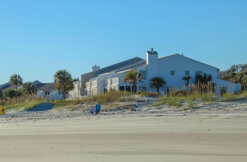 Beachfront houses with palm trees under a clear blue sky, showcasing a serene coastal setting.
