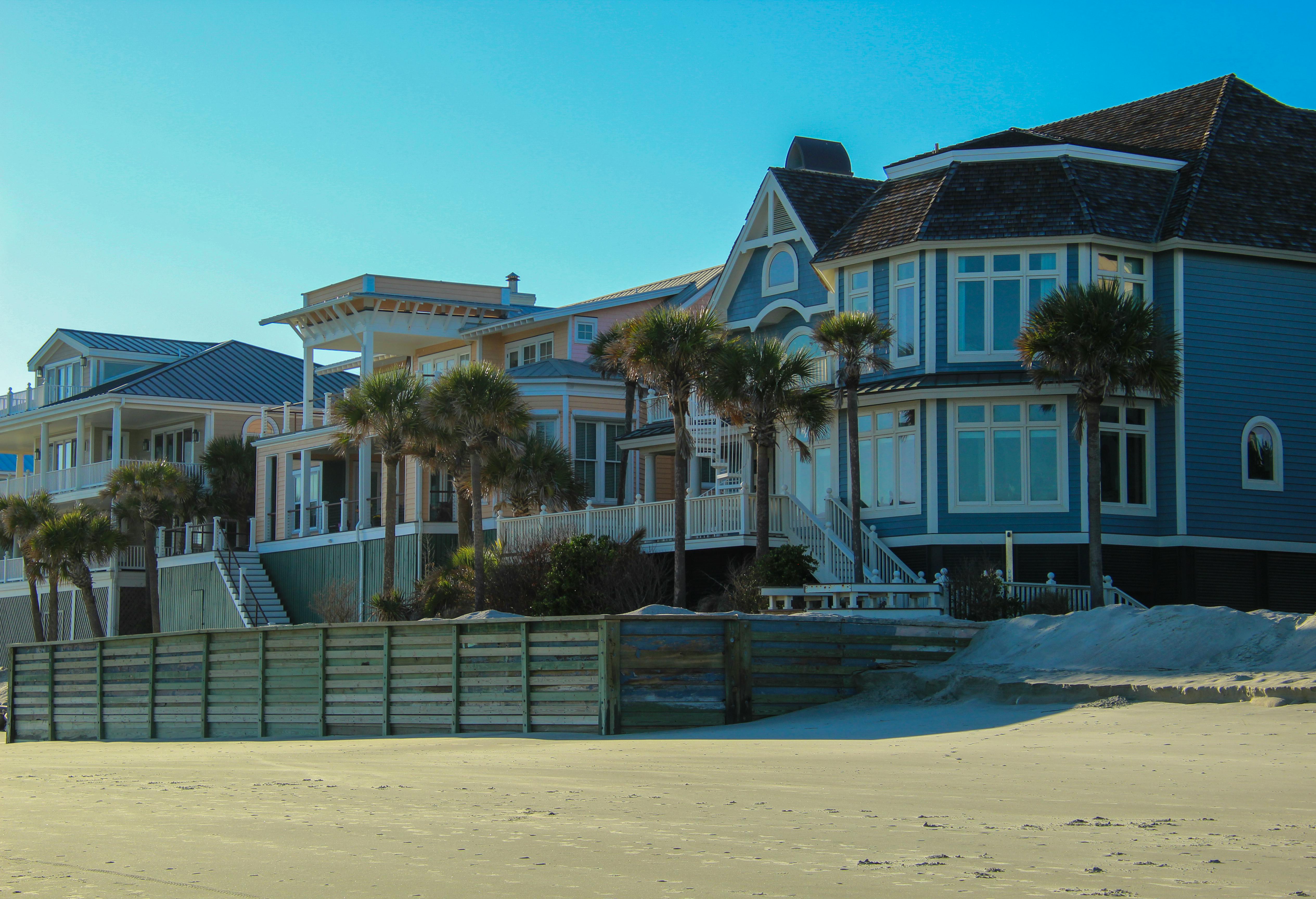 Stunning view of luxurious beachfront homes surrounded by palm trees on the sandy shore.