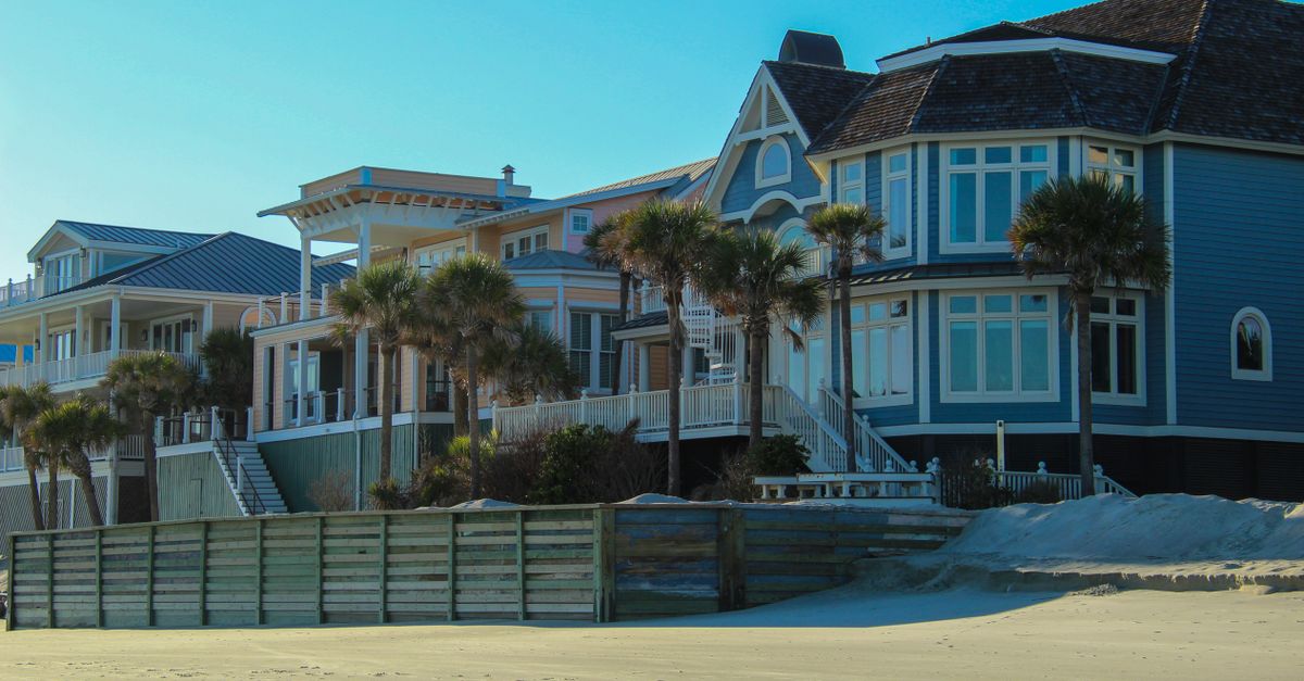 Stunning view of luxurious beachfront homes surrounded by palm trees on the sandy shore.