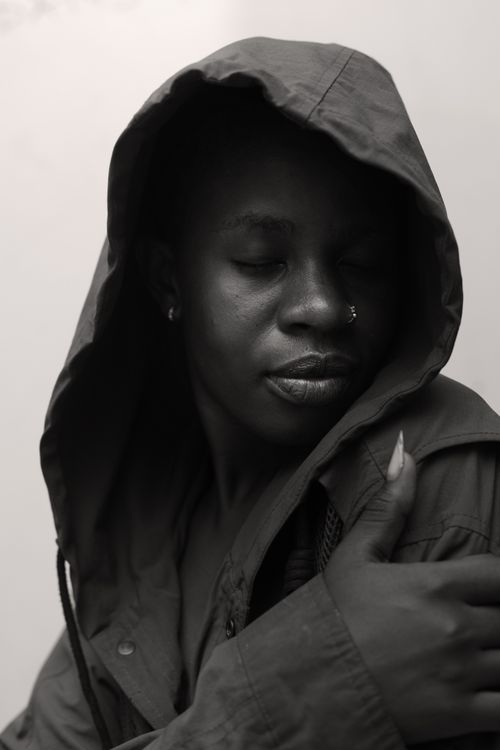 Free Black and white portrait of a person in a hooded jacket, eyes closed, serene expression. Stock Photo