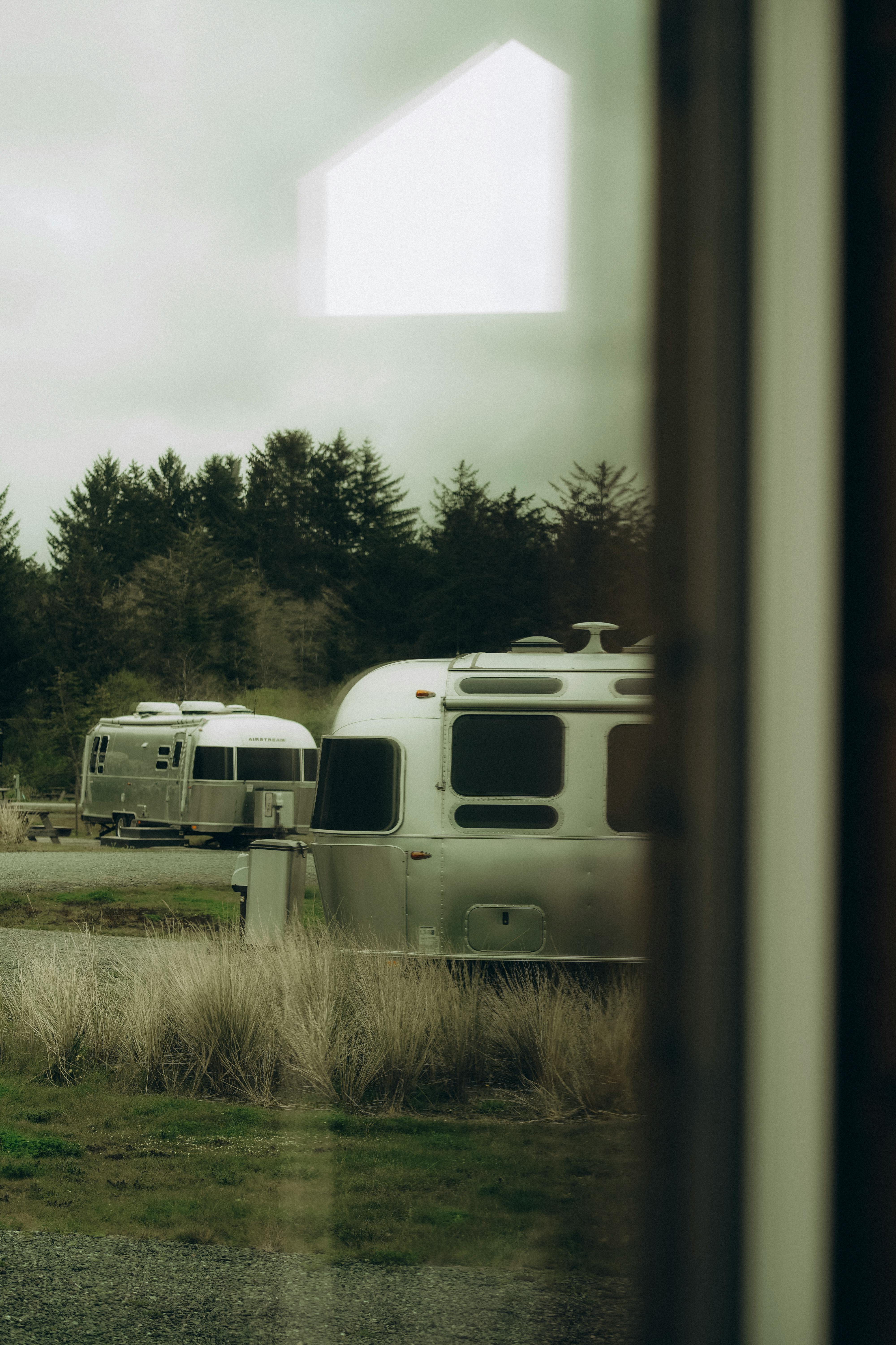 A quiet state park campground with pine trees, a lake shoreline, and a small RV site at sunrise