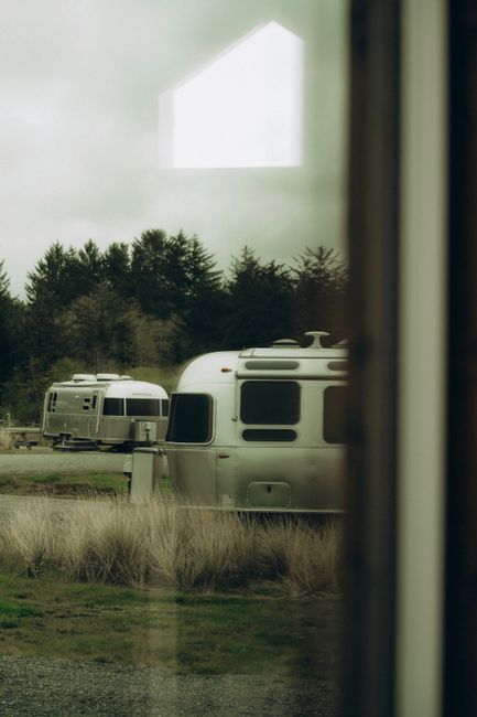 A quiet state park campground with pine trees, a lake shoreline, and a small RV site at sunrise