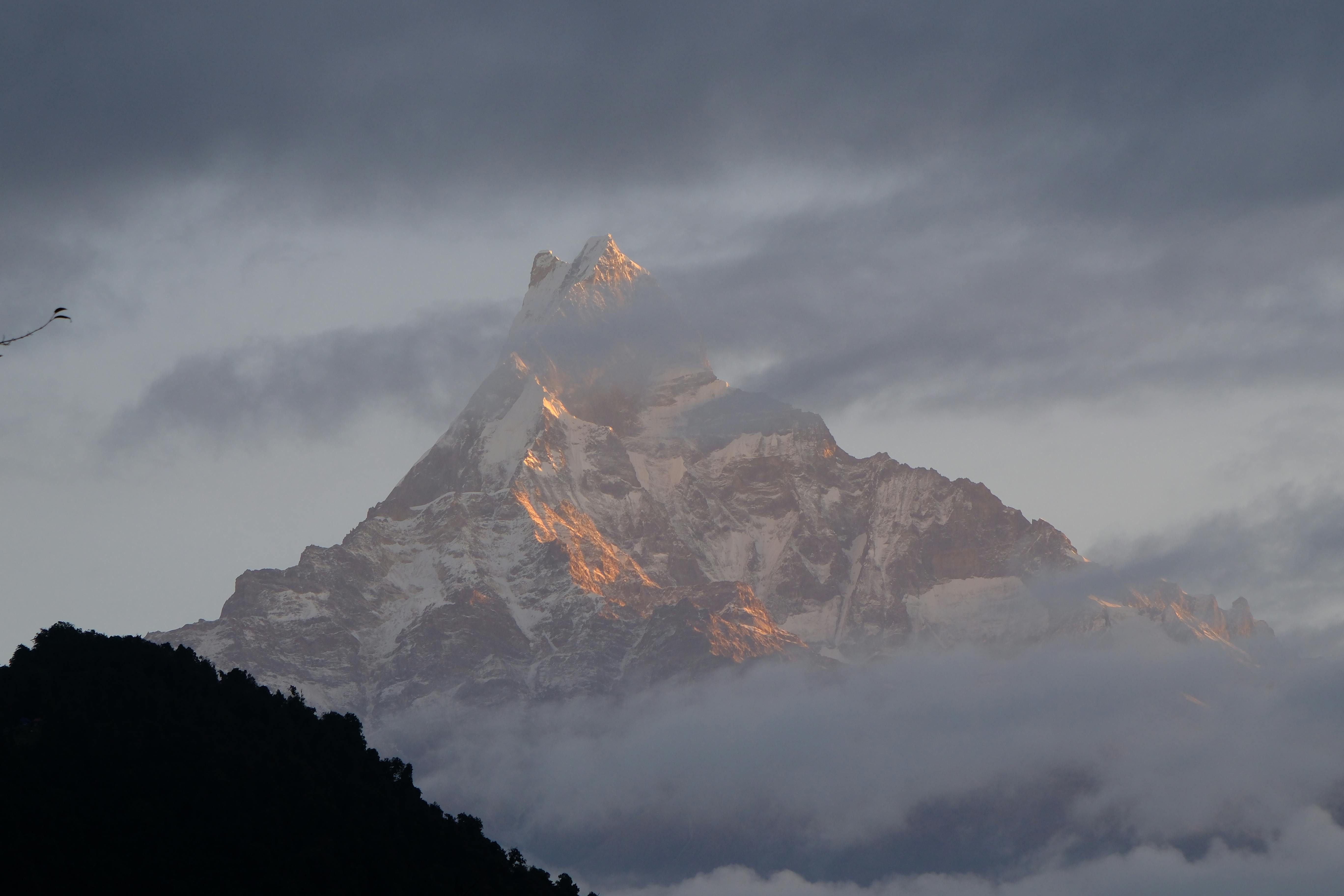 Prescription Goggle Inserts - Machapuchare mountain peak amidst clouds, bathed in sunrise light, creating a dramatic Himalayan landscape.