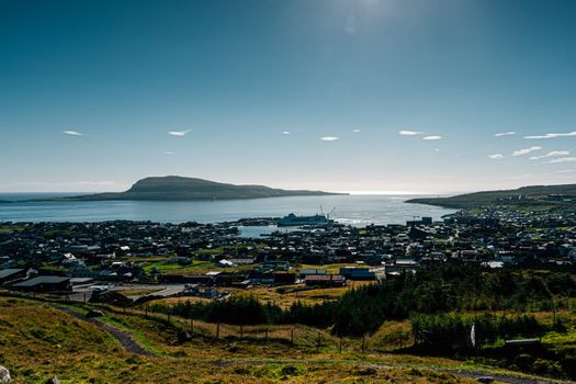 Scenic view of a coastal harbor town with lush greenery and a clear blue sky.