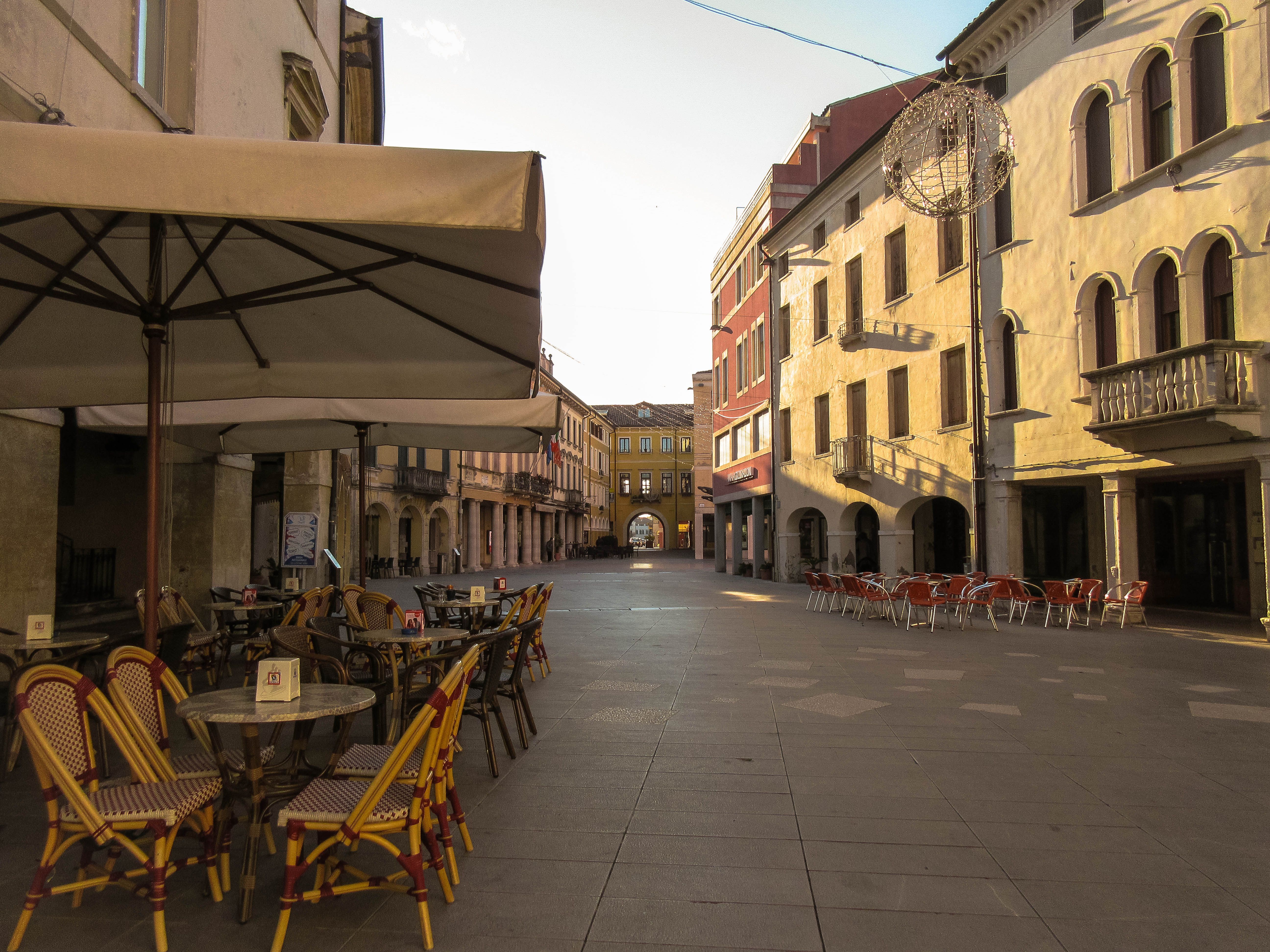 Quiet European street with outdoor cafes and historic buildings at dusk.