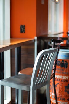 Empty pizzeria seating area in Toronto with vibrant orange decor and modern chairs.