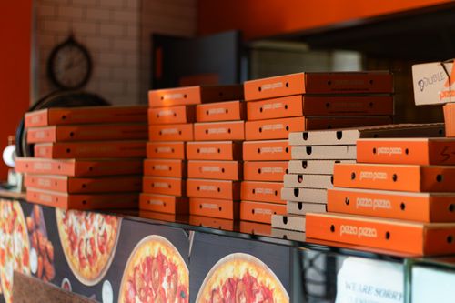 Free Orange pizza boxes stacked in a Toronto pizzeria, showcasing vibrant packaging. Stock Photo