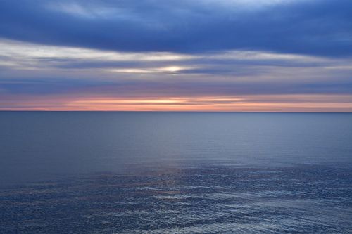 Free Serene ocean view under dramatic twilight sky with soft pastel colors blending into the horizon. Stock Photo