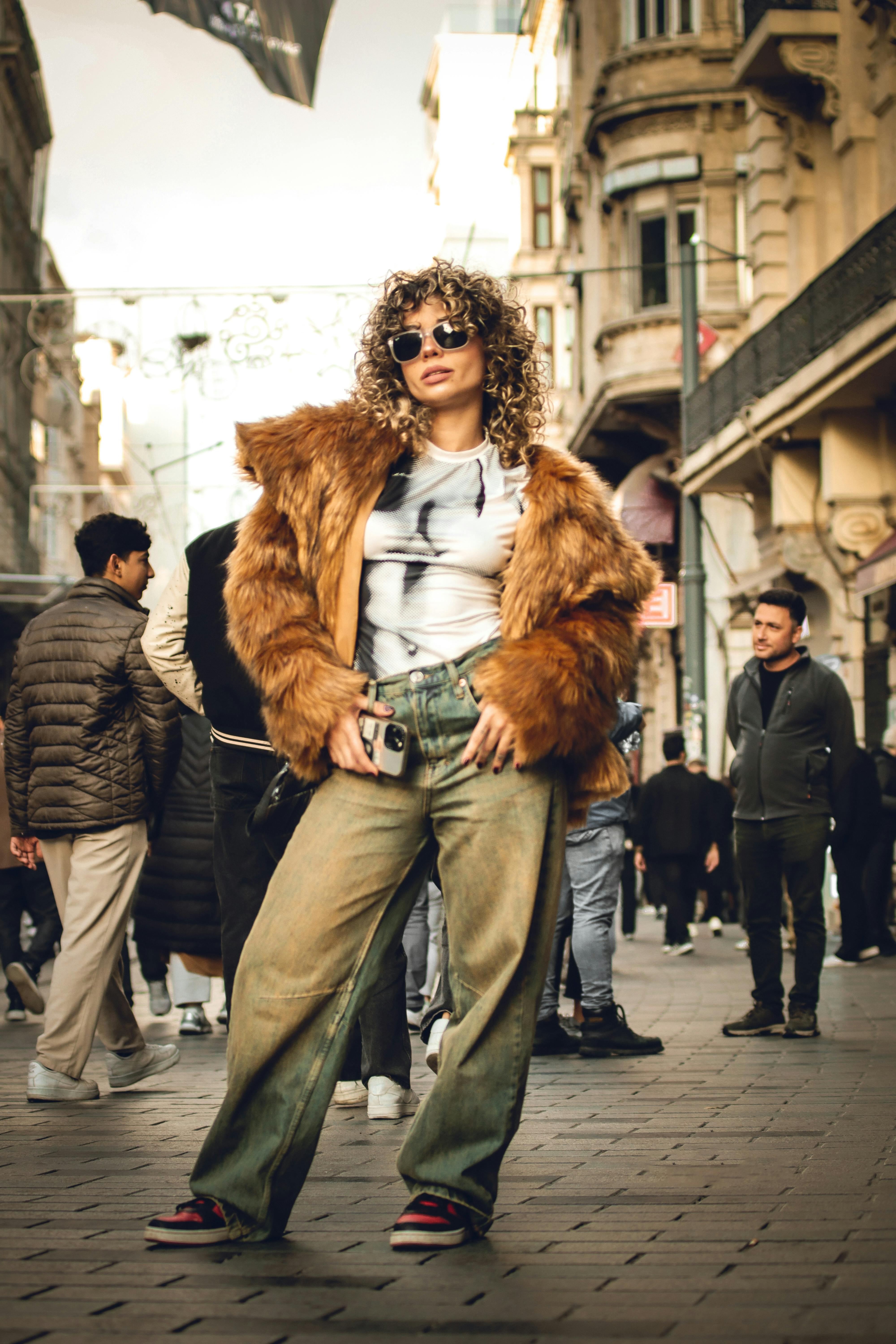 Free Stylish woman wearing fur coat poses confidently in bustling city street. Stock Photo