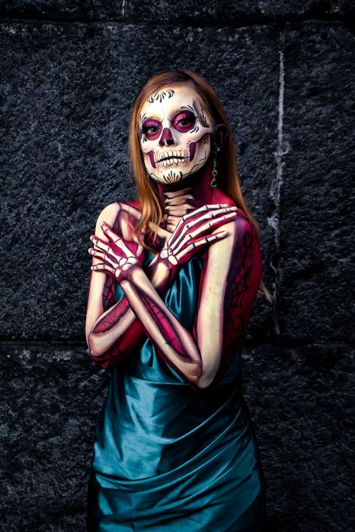 Free A woman in vibrant Catrina makeup against a stone wall, embodying Day of the Dead elegance. Stock Photo