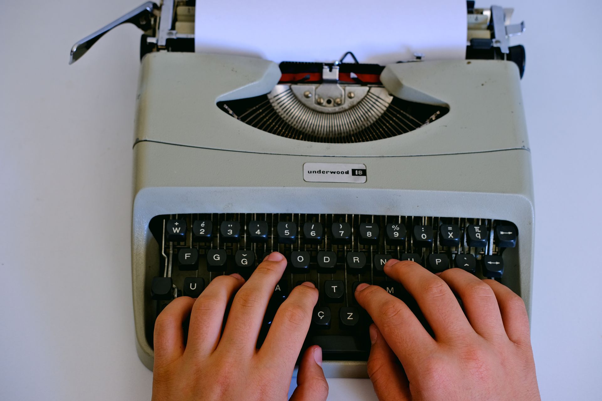 Close-up of hands typing on a classic Underwood typewriter with paper.