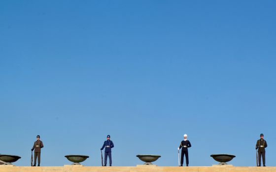 Uniformed guards standing at Anıtkabir in Ankara under a clear blue sky.