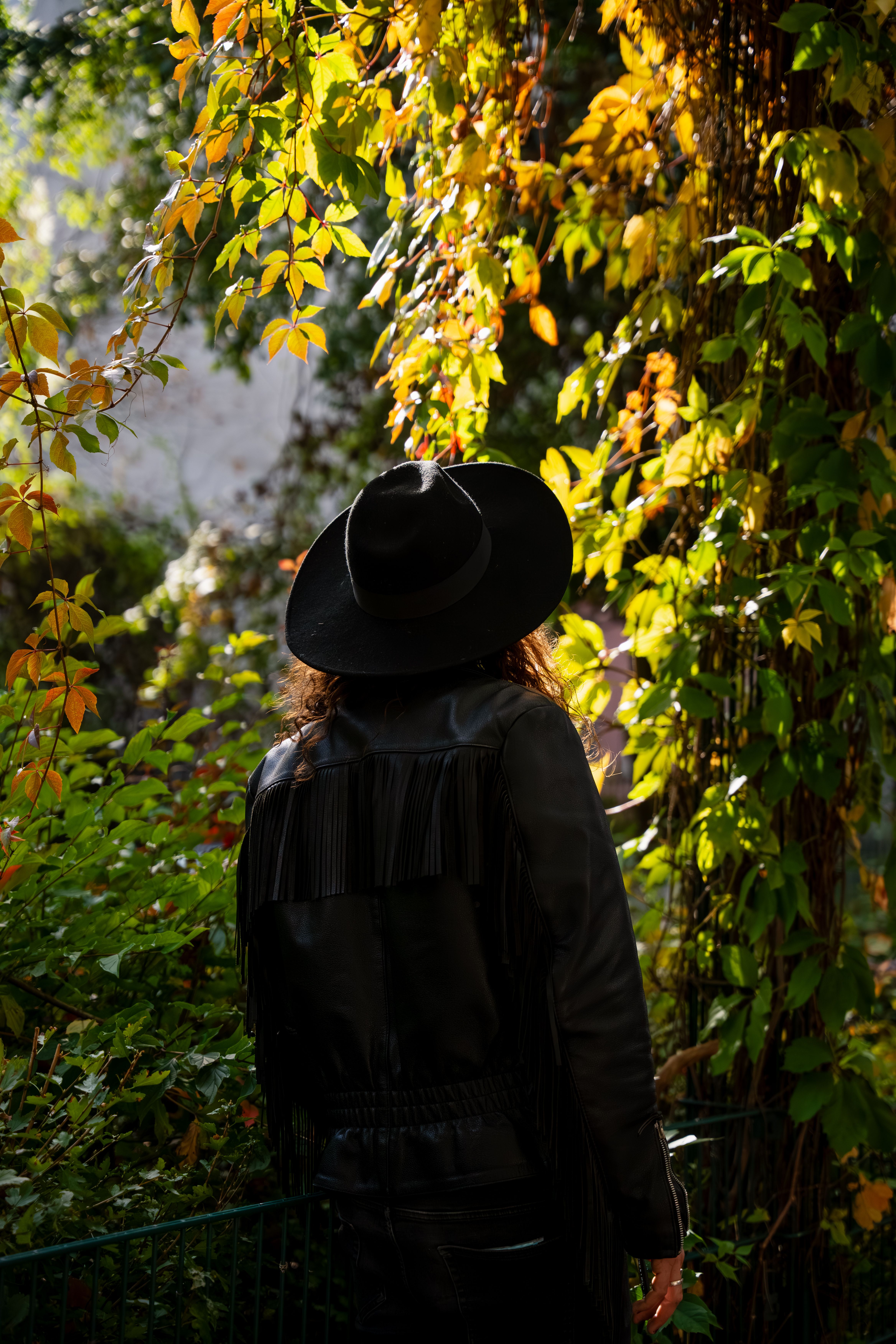 A fashionable man in a hat and jacket, surrounded by vibrant autumn foliage in Berlin.