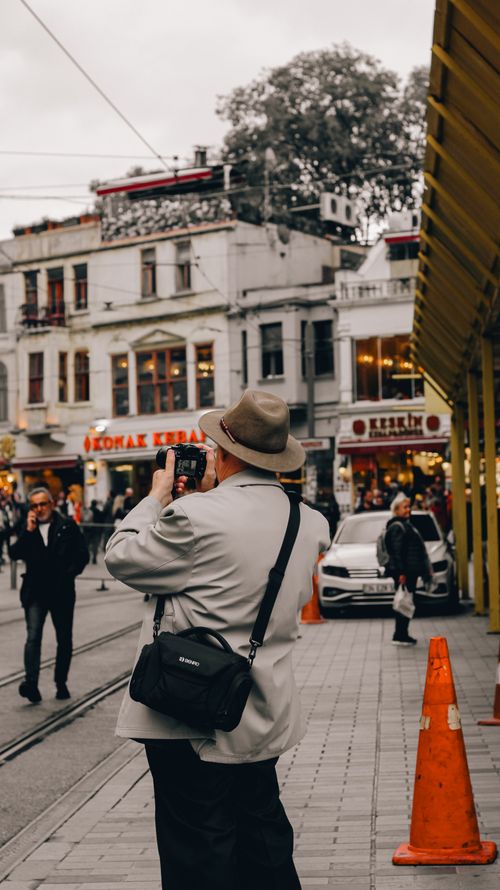 Free A photographer captures a vibrant city street atmosphere filled with people and shops. Stock Photo