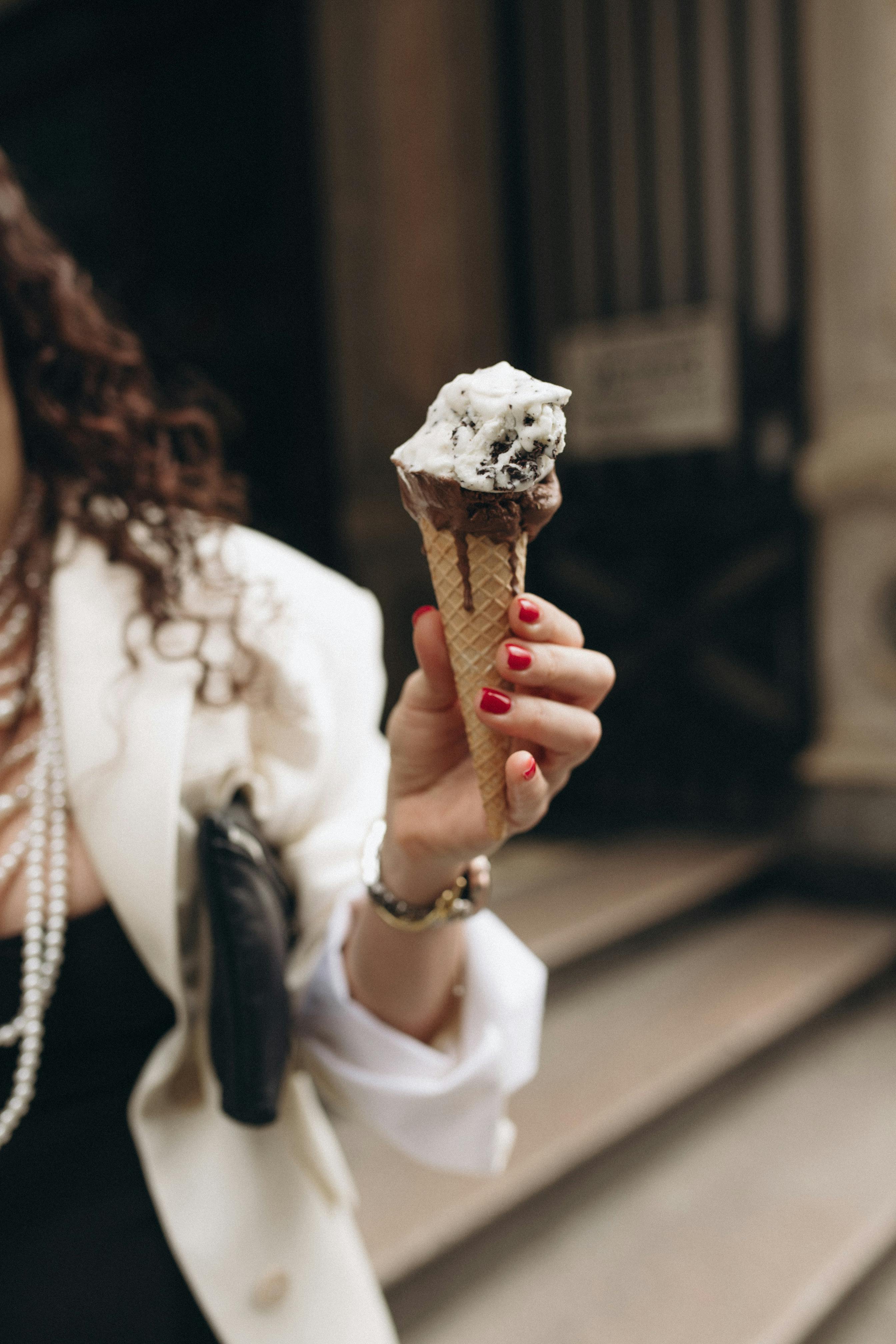 A woman holds melting ice cream on the street, capturing a moment of indulgence.