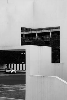 Black and white photo of geometric urban architecture with a parked car, creating a modern composition.