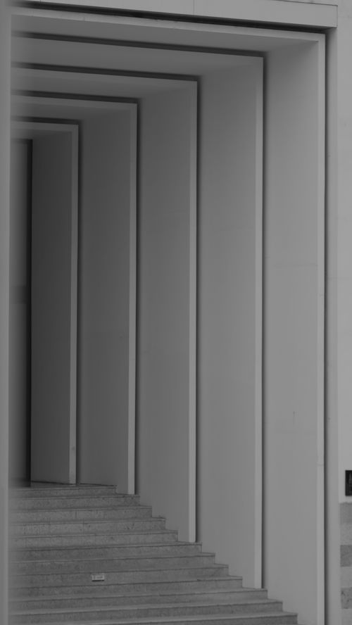 Free Black and white abstract photo of geometric archways creating a tunnel effect with stairs. Stock Photo
