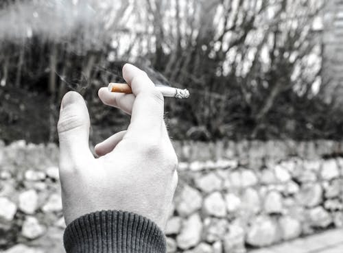 Gratis Fotografi Warna Selektif Orang Yang Memegang Batang Rokok Foto Stok