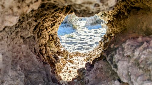 Free View of a sandy beach through a natural rock formation, capturing erosion effects. Stock Photo