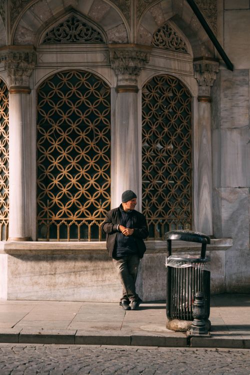 Free A man leans against a wall with intricate designs in an urban setting. Stock Photo