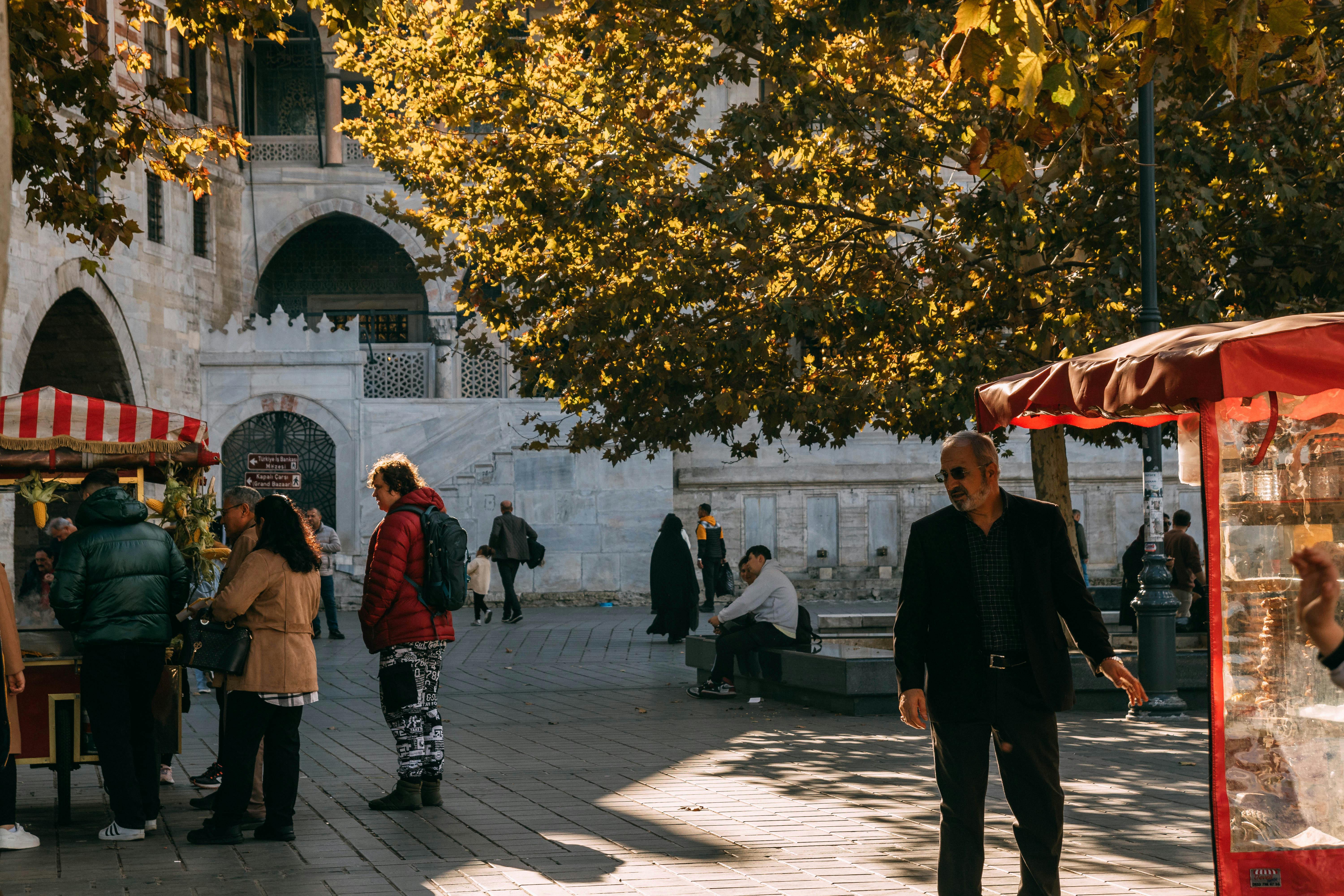 People enjoying a vibrant autumn day market by a historic building.
