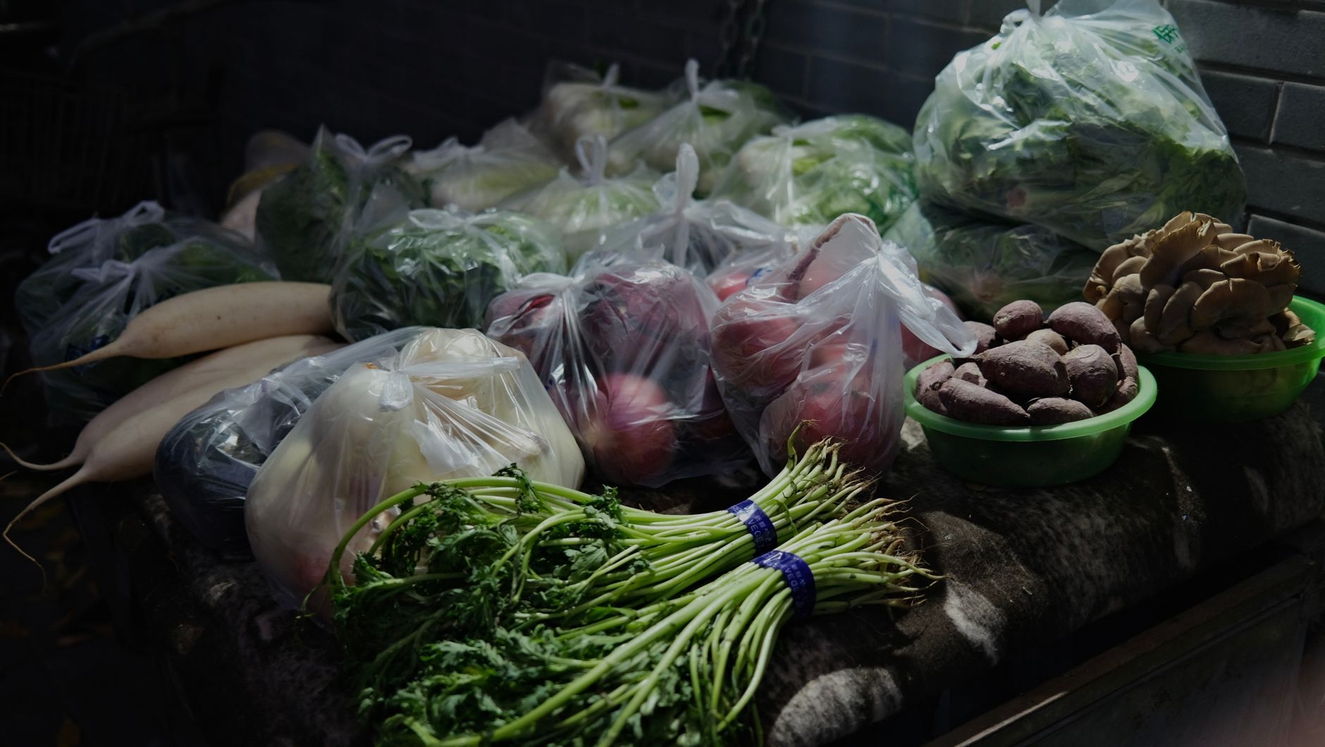 Assorted fresh vegetables and root produce neatly packaged in a market setting.