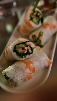 Fresh Vietnamese spring rolls with shrimp, herbs, and vegetables on a plate.