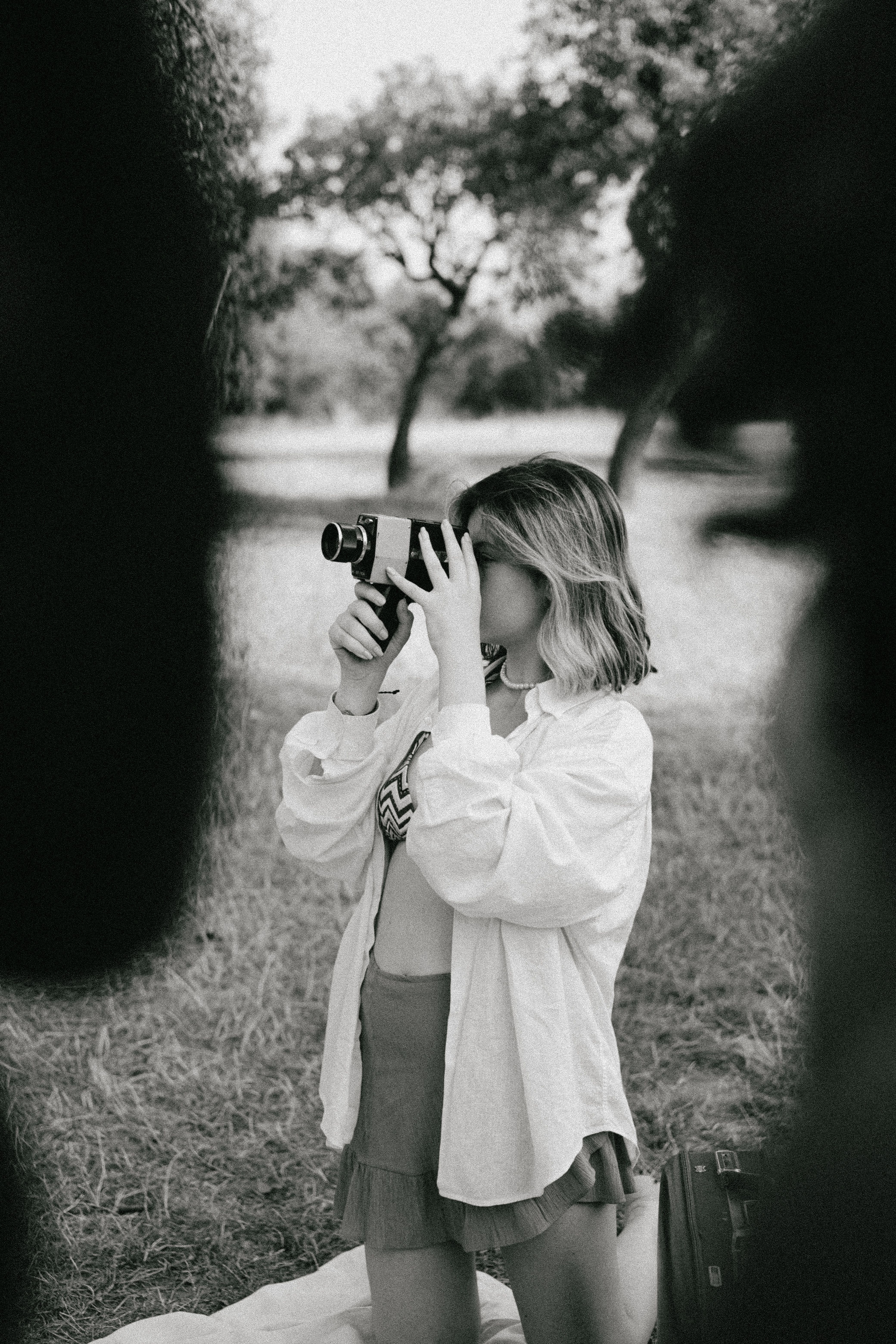 A young woman using a vintage camera in a serene outdoor setting.