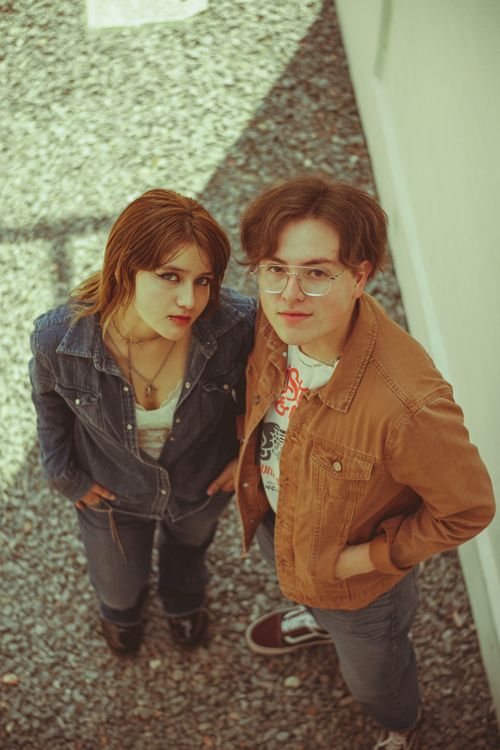 Free Overhead view of two young adults standing together outdoors wearing casual denim and jackets. Stock Photo