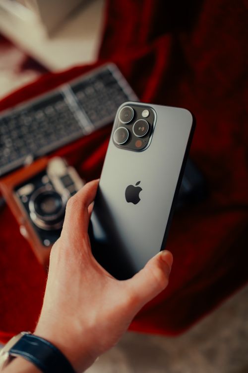 Free Close-up of a modern smartphone held above a vintage camera on a textured background. Stock Photo