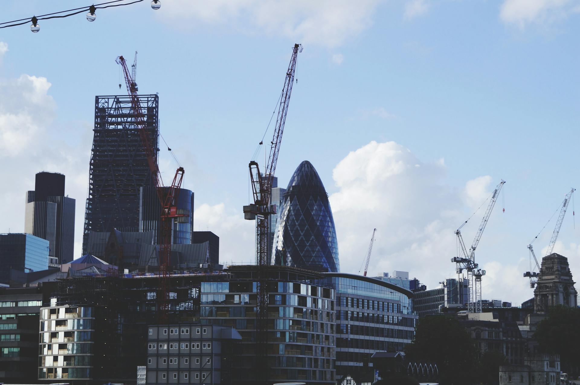 Iconic London skyline featuring skyscrapers and construction cranes on a clear day.