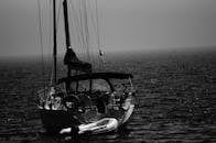 在平静的海水中，一艘帆船和一艘小艇漂流在宁静的黑白照片里