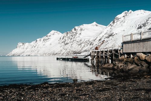 Free Snow-covered mountains and a calm bay in Northern Norway under a clear blue sky. Stock Photo