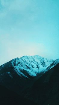 Stunning snow-covered mountain peaks under a vibrant blue sky, showcasing natural beauty.