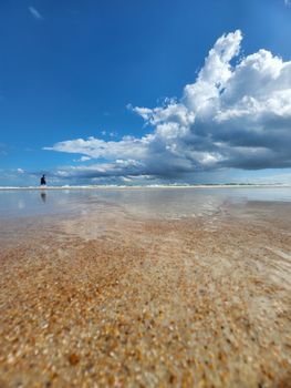 Sandy beach with calm waves and a vibrant blue sky. Perfect for summer themes.