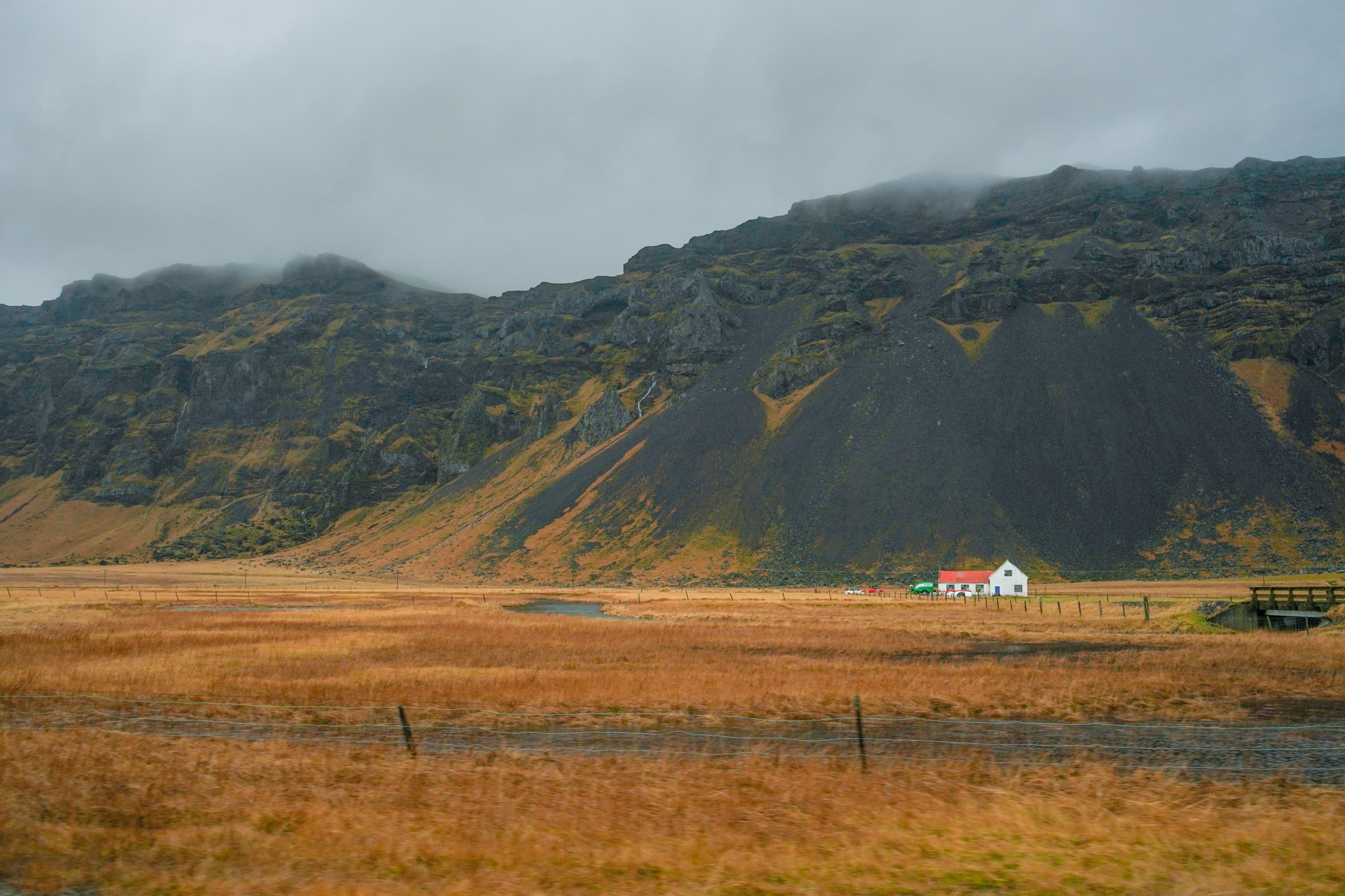 Gratis Naturskøn udsigt over et fjerntliggende hus beliggende ved bjerge i Island Lagerfoto
