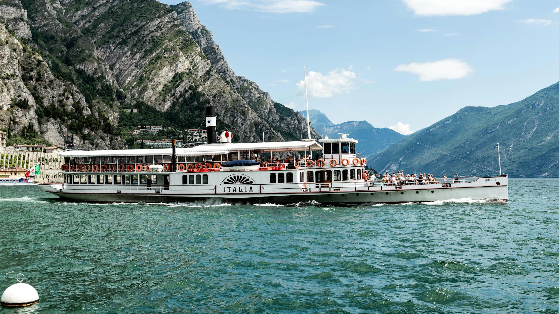 Historic steamboat cruising on Lake Garda with mountains in the background.