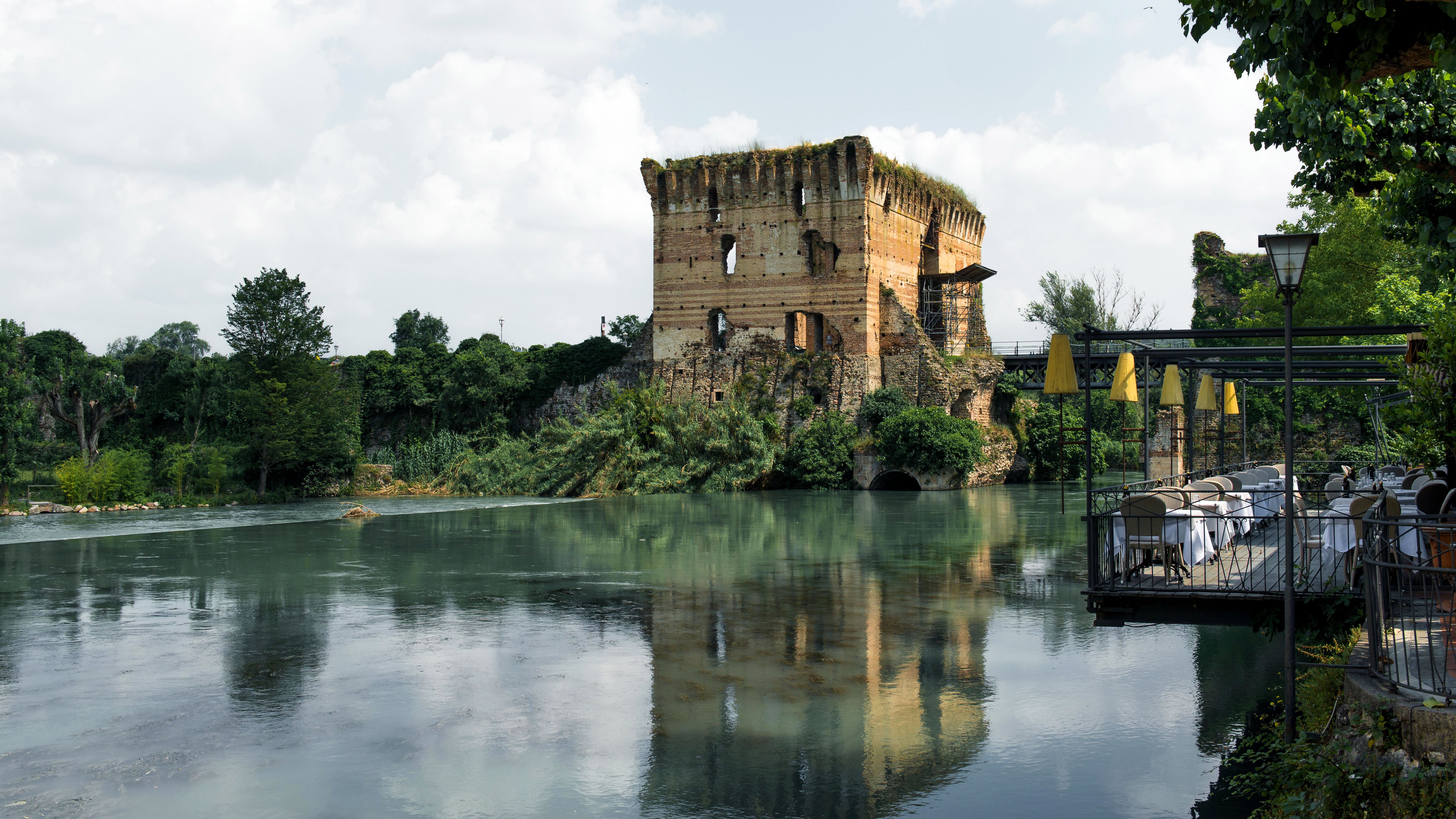Explore the enchanting old castle ruins by the serene lake in Valeggio sul Mincio, Italy, a perfect travel destination.