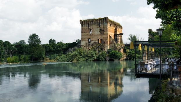 Explore the enchanting old castle ruins by the serene lake in Valeggio sul Mincio, Italy, a perfect travel destination.